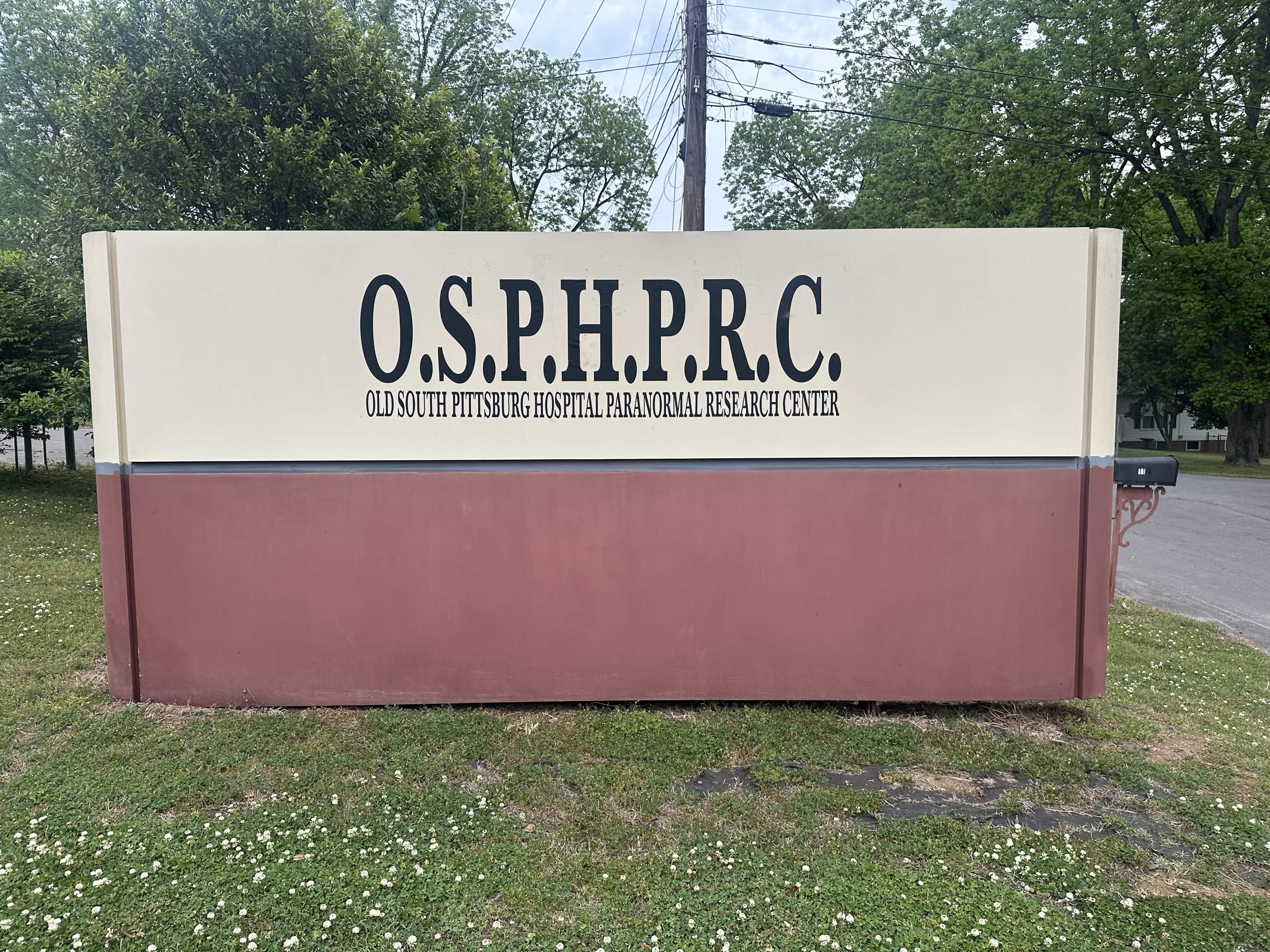A free-standing monument sign at the entrance to the property reading O.S.P.H.P.R.C., Old South Pittsburg Hospital Paranormal Research Center